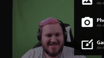 A Man With Pink Hair Is Sitting In Front Of A Green Screen . GIF