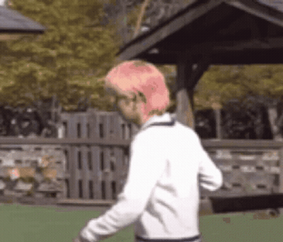 A Man With Pink Hair Is Walking In Front Of A Gazebo . GIF