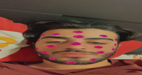 A Man With Pink Smiley Faces On His Face Laying On A Bed GIF