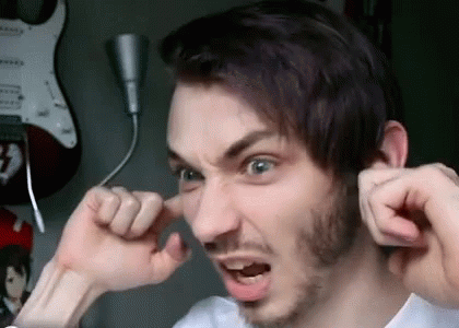 A Man With Purple Hair And A Beard Is Plugging His Ears . GIF