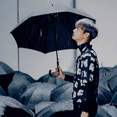 A Man With Purple Hair Is Holding A Black Umbrella GIF