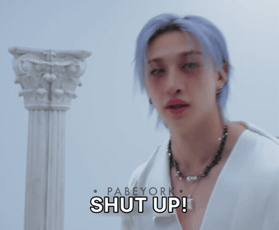A Man With Purple Hair Is Holding A Hammer In Front Of A Sign That Says " Shut Up " GIF