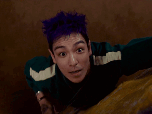 A Man With Purple Hair Is Holding A Spinner GIF