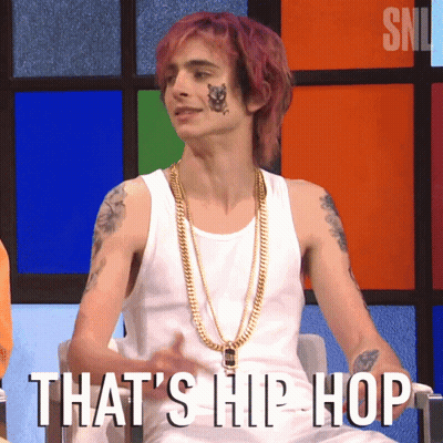 A Man With Purple Hair Is Wearing A White Tank Top And Gold Chains With The Words That 'S Hip Hop Written Below Him GIF