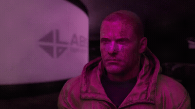 A Man With Purple Paint On His Face Is Standing In Front Of A Lab Sign GIF