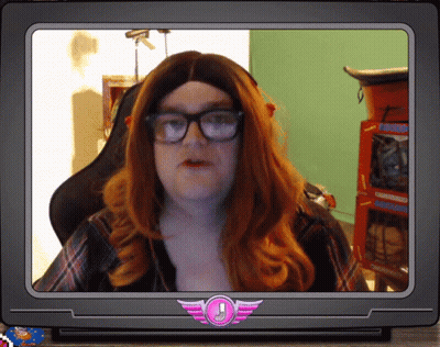 A Man With Red Hair And Glasses Is On A Tv Screen With A Pink Emblem With An Exclamation Point GIF