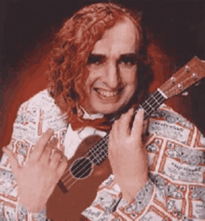 A Man With Red Hair Is Holding A Guitar And Giving A Middle Finger GIF