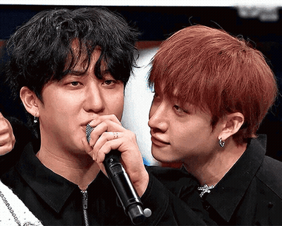 A Man With Red Hair Is Holding A Microphone Next To Another Man GIF