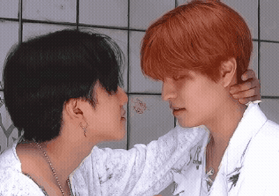 A Man With Red Hair Is Kissing A Woman With Black Hair GIF