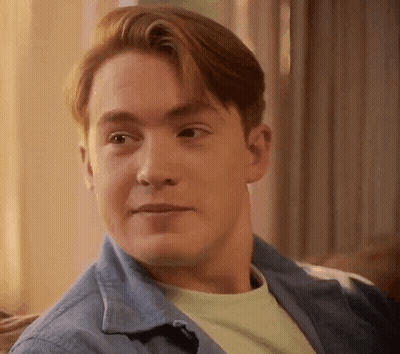 A Man With Red Hair Is Sitting On A Couch And Smiling . GIF