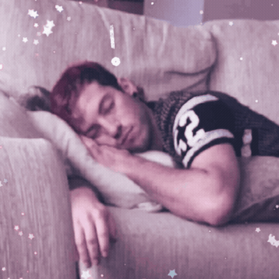 A Man With Red Hair Is Sleeping On A Couch With A Shirt That Says Rc On It GIF