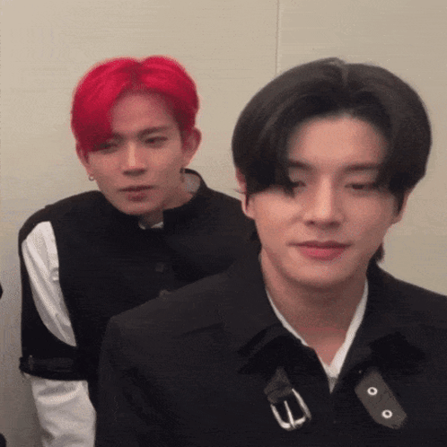 A Man With Red Hair Is Standing Next To Another Man In A Black Jacket GIF