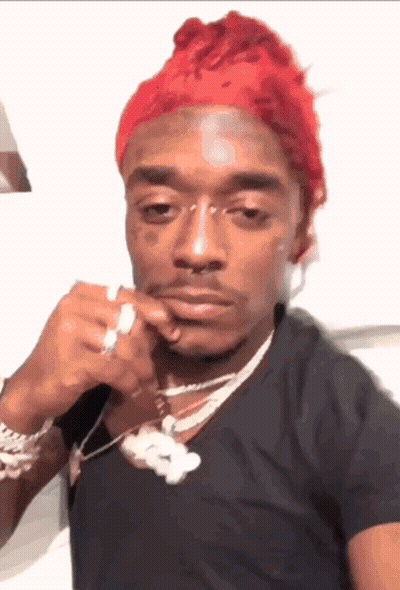 A Man With Red Hair Is Wearing A Black Shirt And A Silver Necklace GIF