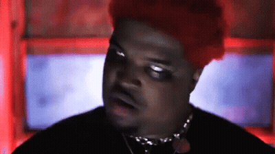 A Man With Red Hair Is Wearing A Black Shirt And Necklace . GIF