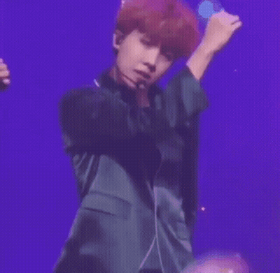 A Man With Red Hair Is Wearing A Microphone And Smiling While Standing On A Stage . GIF