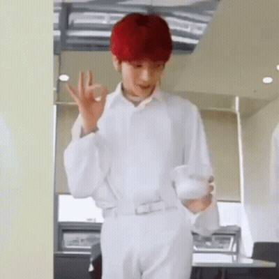 A Man With Red Hair Is Wearing A White Shirt And White Pants And Is Holding A Cup Of Coffee . GIF