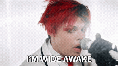A Man With Red Hair Singing Into A Microphone With The Words " I 'M Wide Awake " Behind Him GIF
