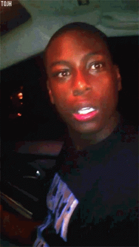 A Man With Red Lipstick On His Lips Is Wearing A Black Shirt With The Word Tjah On It GIF