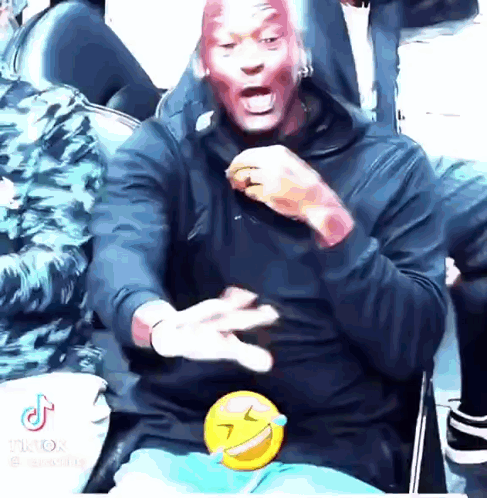 A Man With Red Paint On His Face Is Sitting In A Chair With A Smiley Face On His Lap . GIF