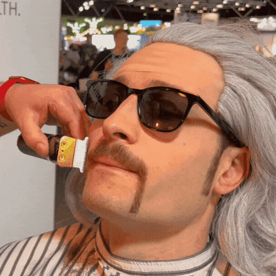A Man With Sunglasses And A Mustache Is Getting His Beard Trimmed GIF