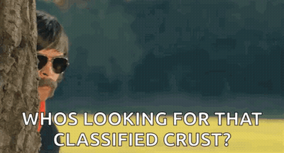A Man With Sunglasses And A Mustache Is Peeking Out From Behind A Tree And Asking Who Is Looking For That Classified Cru GIF