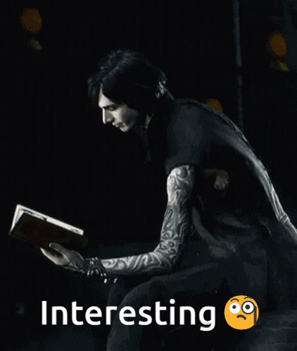 A Man With Tattoos Is Reading A Book In The Dark GIF