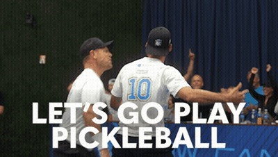 A Man With The Number 10 On His Back Is Hugging Another Man In Front Of A Sign That Says Let 'S Go Play Pickleball GIF