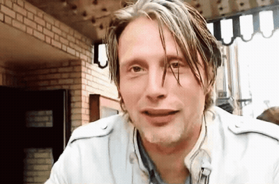 A Man With Wet Hair Is Sitting In Front Of A Brick Wall And Looking At The Camera . GIF