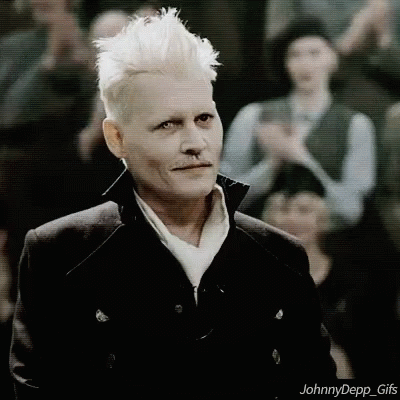 A Man With White Hair And A Nose Ring Is Standing In Front Of A Crowd And Looking At The Camera . GIF