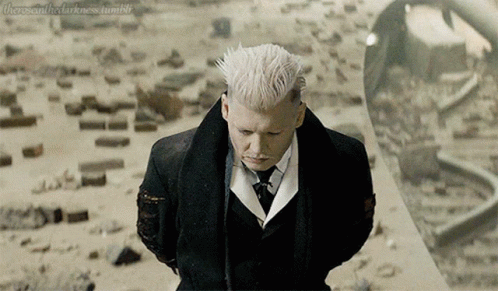 A Man With White Hair In A Suit And Tie Stands In Front Of A Mirror GIF