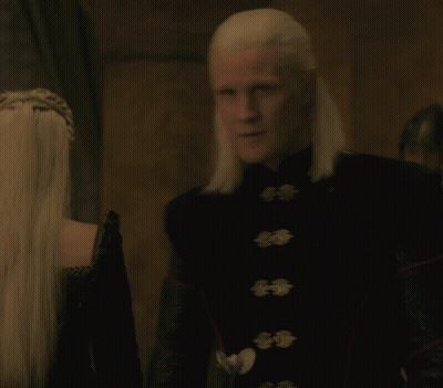 A Man With White Hair Is Wearing A Black Jacket With Buttons GIF