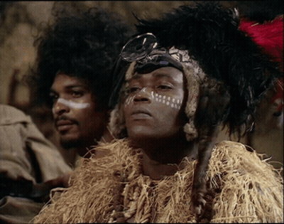 A Man With White Paint On His Face And A Feathered Headdress GIF