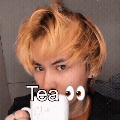 A Man With Yellow Hair Drinking A Cup Of Tea With Googly Eyes GIF
