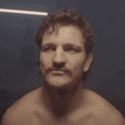 A Man Without A Shirt Has A Mustache And Looks At The Camera GIF