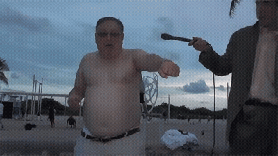 a man without a shirt is being interviewed by a man in a suit holding a microphone