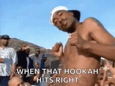 A Man Without A Shirt Is Dancing In Front Of A Crowd Of People . GIF