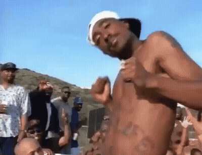 A Man Without A Shirt Is Dancing In Front Of A Crowd Of People . GIF