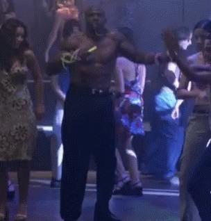A Man Without A Shirt Is Dancing In Front Of A Group Of People GIF