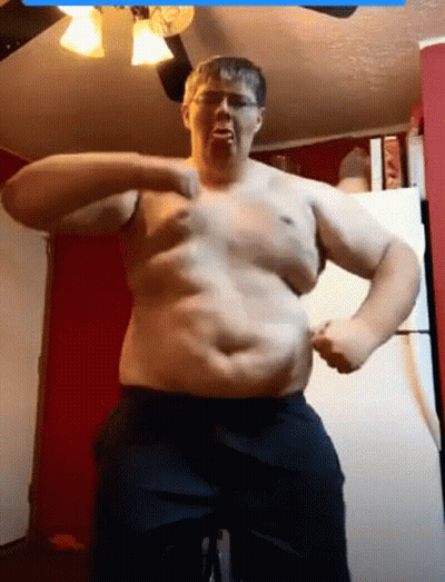 A Man Without A Shirt Is Flexing His Muscles In A Kitchen . GIF