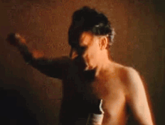 A Man Without A Shirt Is Holding A Bottle Of Beer In His Hand . GIF