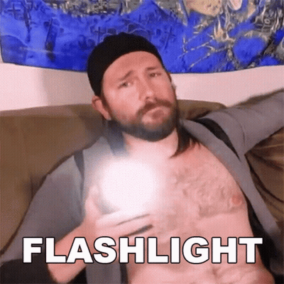 A Man Without A Shirt Is Holding A Flashlight In His Hand And The Word Flashlight Is Above Him GIF