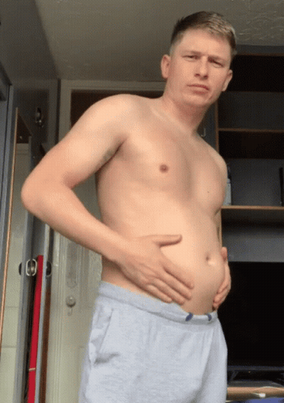 A Man Without A Shirt Is Holding His Belly In Front Of A Door GIF