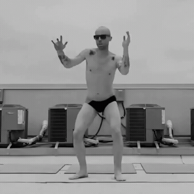 A Man Without A Shirt Is Jumping In The Air In Front Of A Bunch Of Air Conditioners GIF