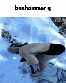 A Man Without A Shirt Is Kneeling Down In The Snow With A Hammer . GIF