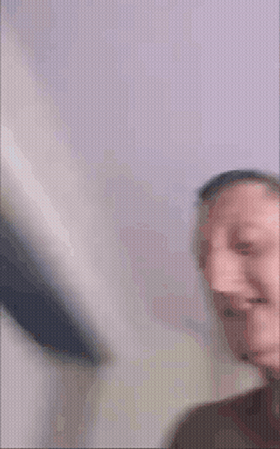 A Man Without A Shirt Is Making A Funny Face While Holding A Book In His Hand . GIF