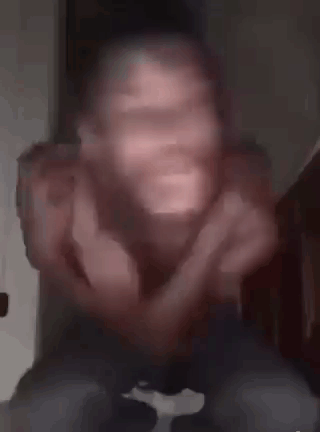 A Man Without A Shirt Is Making A Funny Face While Sitting On A Bed . GIF
