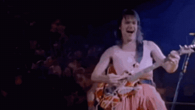 A Man Without A Shirt Is Playing An Electric Guitar On A Stage . GIF