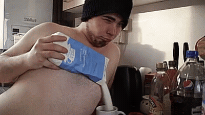 A Man Without A Shirt Is Pouring Milk From A Carton GIF