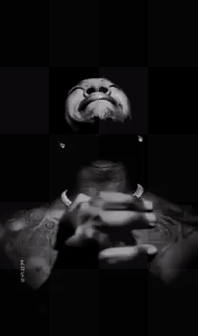 A Man Without A Shirt Is Praying With His Hands Folded In Front Of His Face . GIF