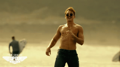 A Man Without A Shirt Is Running On A Beach With A Top Gun Maverick Logo Behind Him GIF